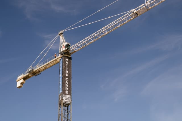 Vue extérieure d'une grue de chantier et sa bannière Maître Carré